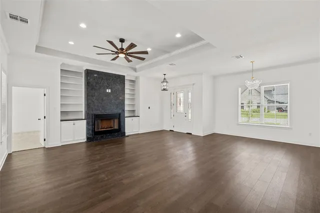 an empty room with wooden floor chandelier fan and windows