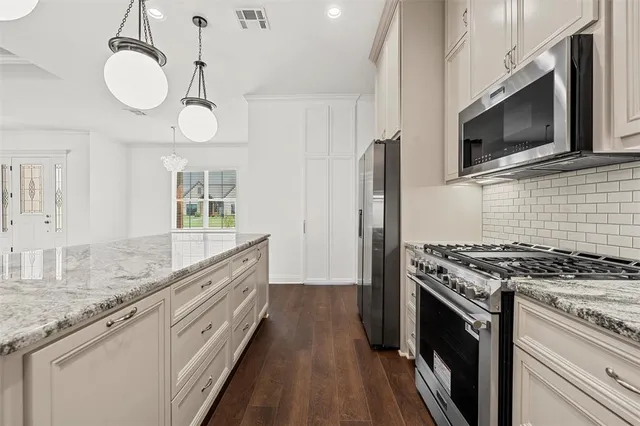 a kitchen with stainless steel appliances granite countertop a stove a sink and a microwave
