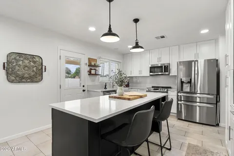 a kitchen with stainless steel appliances a stove a sink a refrigerator a center island a table and chairs