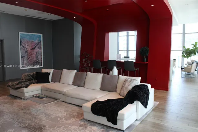 a living room with furniture large window and wooden floor