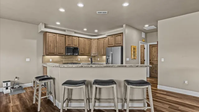 a kitchen with kitchen island granite countertop wooden cabinets and stainless steel appliances