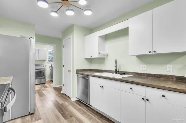 a kitchen with granite countertop a sink stainless steel appliances and cabinets