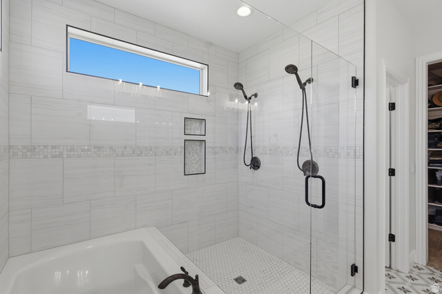 10676 Urban Rdg Cove South Jordan, UT 84095 - Photo 14 of 48 Spacious bathroom featuring a glass-enclosed shower with dual shower heads, an integrated soaking tub, and a horizontal transom window