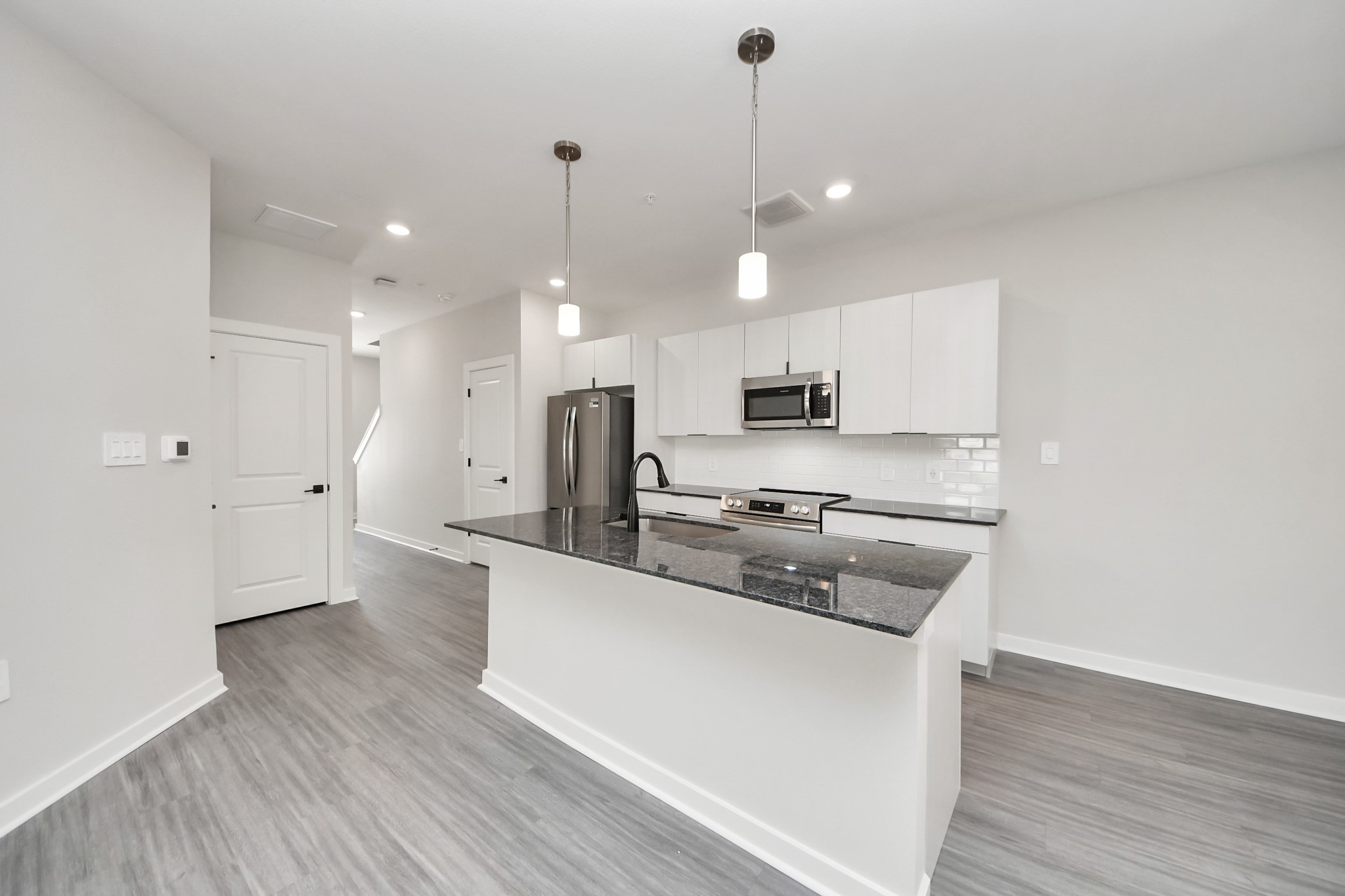 7711 Longmire Road, Unit 102 Conroe, TX 77304 - Photo 42 of 48 a large kitchen with stainless steel appliances a large counter top a stove a sink dishwasher and a refrigerator with wooden floor