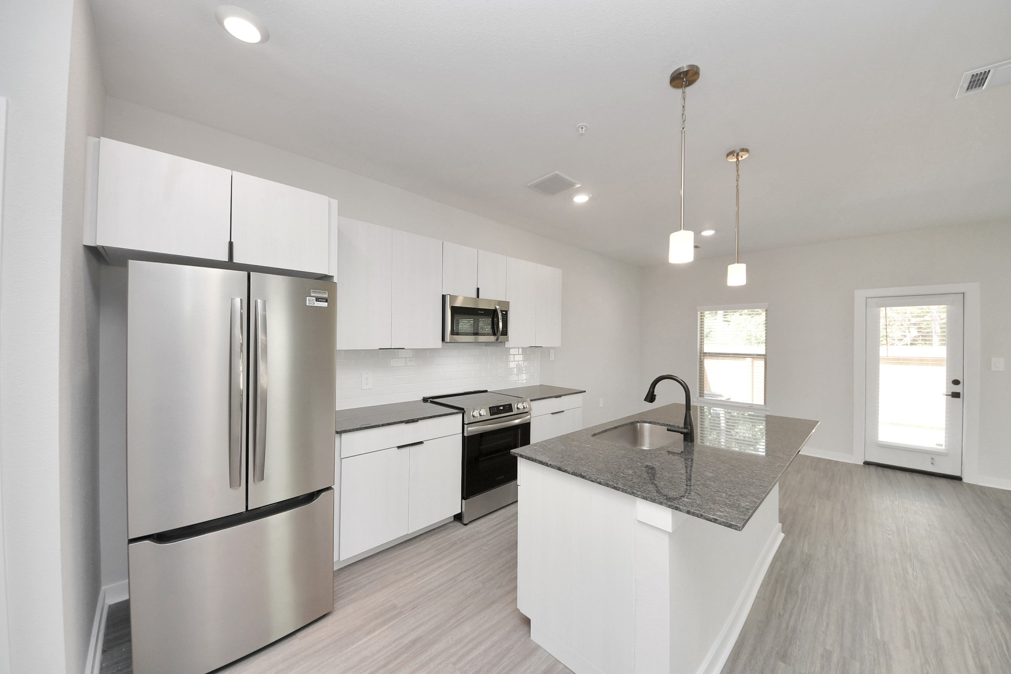 7711 Longmire Road, Unit 102 Conroe, TX 77304 - Photo 43 of 48 a kitchen with stainless steel appliances granite countertop a refrigerator a sink a stove and a wooden floors