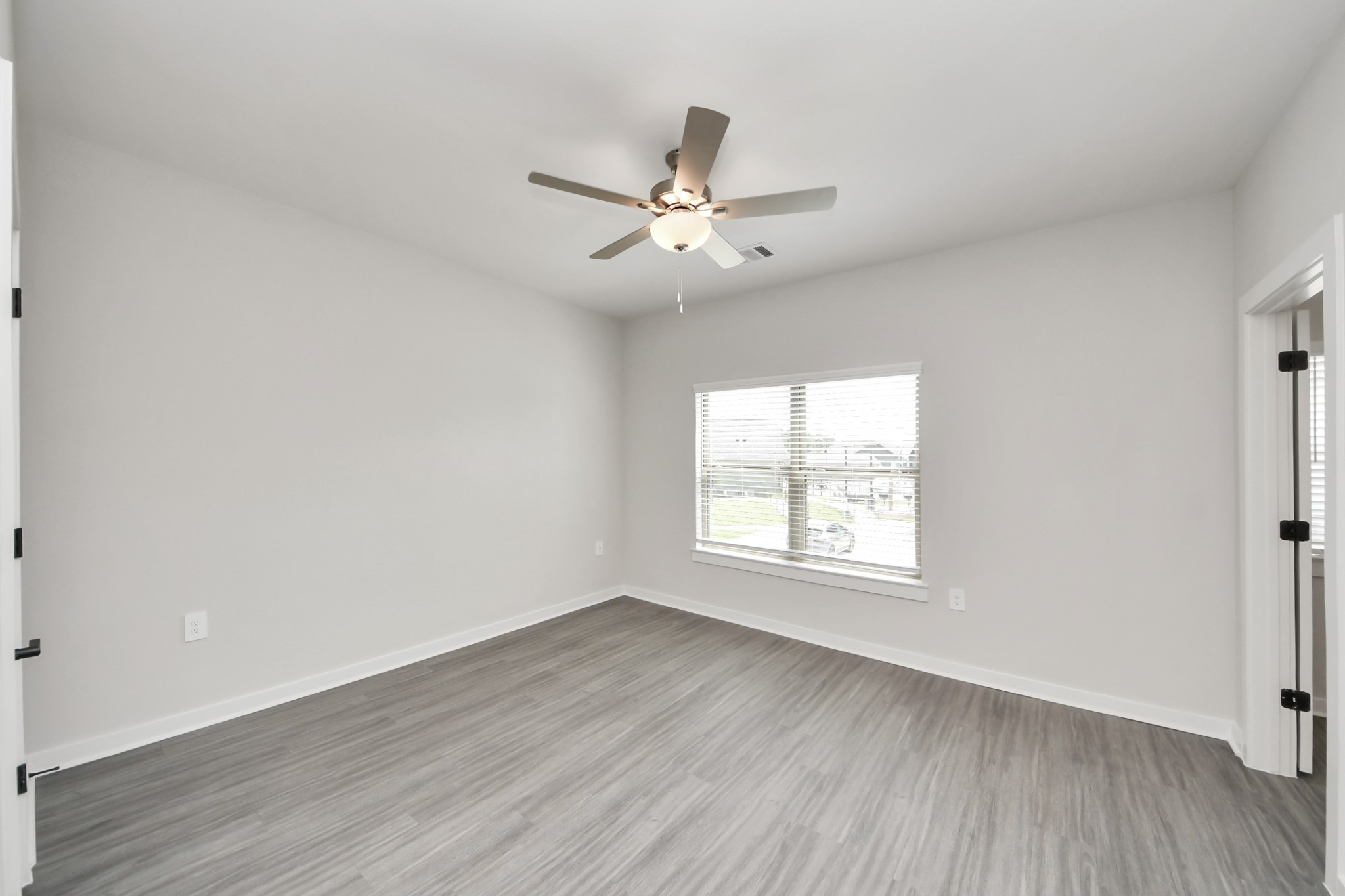 7711 Longmire Road, Unit 102 Conroe, TX 77304 - Photo 15 of 48 an empty room with wooden floor fan and windows