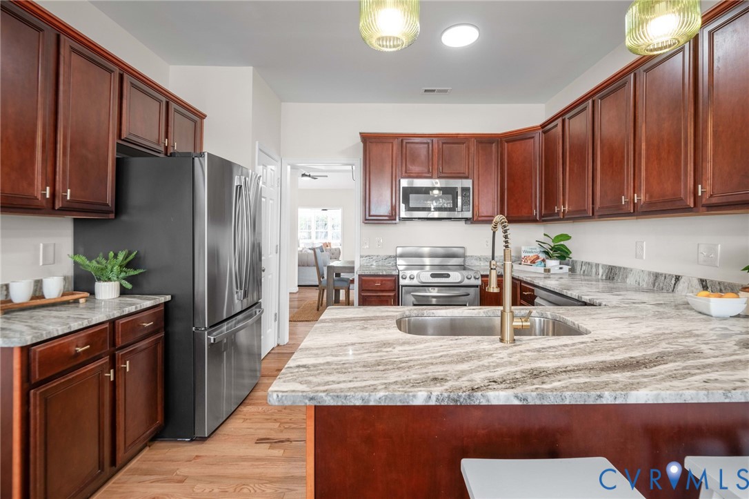 1024 Alcorn Terrace Midlothian, VA 23114 - Photo 12 of 50 a kitchen with granite countertop a sink a refrigerator and a wooden cabinets