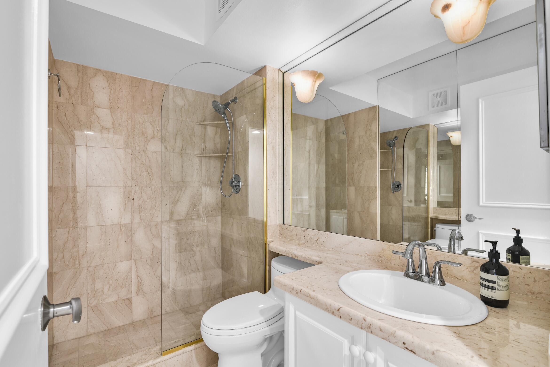 277 North Ocean Boulevard, Unit 1010 Boca Raton, FL 33432 - Photo 14 of 30 a bathroom with a granite countertop sink a toilet and shower