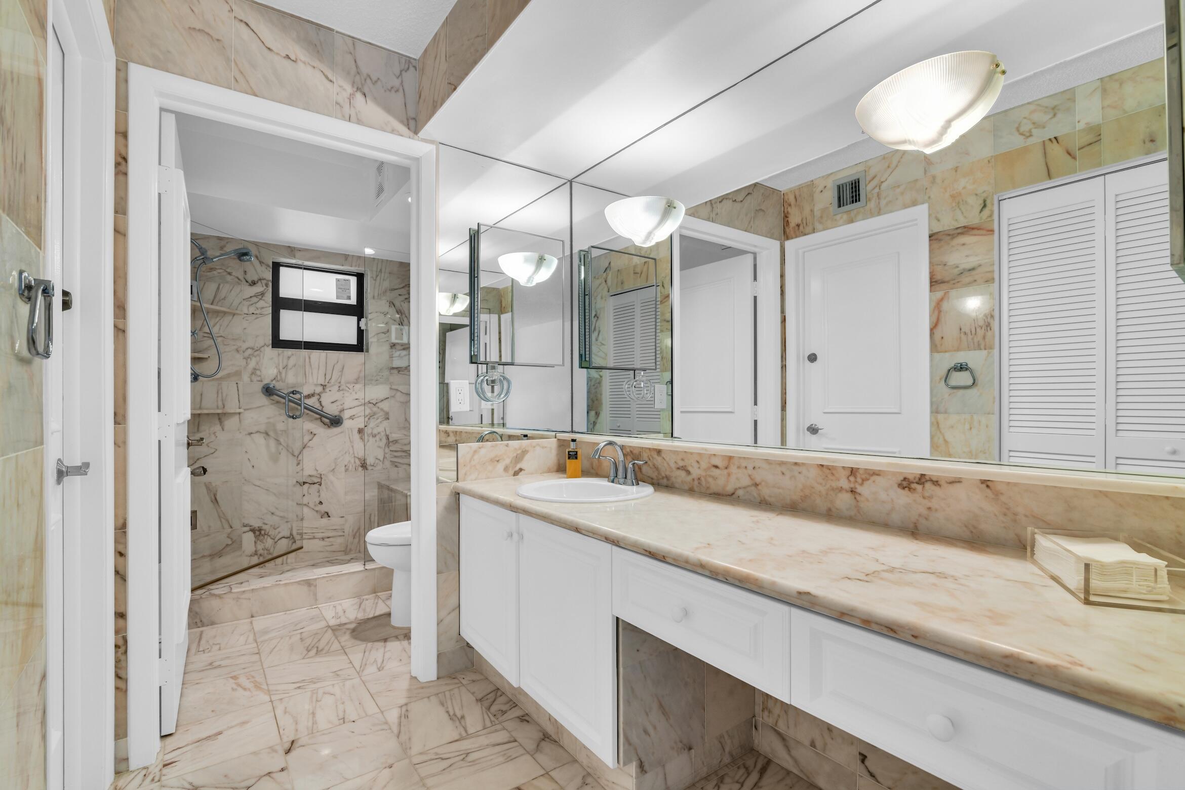 277 North Ocean Boulevard, Unit 1010 Boca Raton, FL 33432 - Photo 16 of 30 a bathroom with a granite countertop sink a toilet and shower