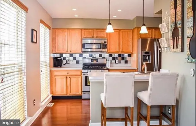 a kitchen with stainless steel appliances kitchen island granite countertop a stove a sink a dining table and chairs