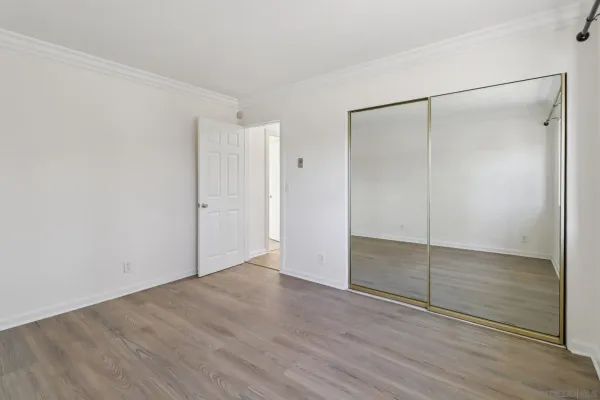 an empty room with wooden floor and mirror