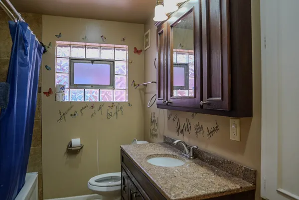 a bathroom with a granite countertop toilet sink and mirror