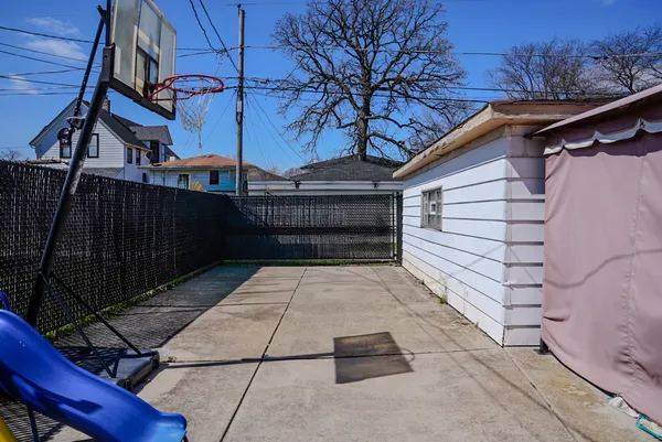 a view of backyard with wooden fence and large trees