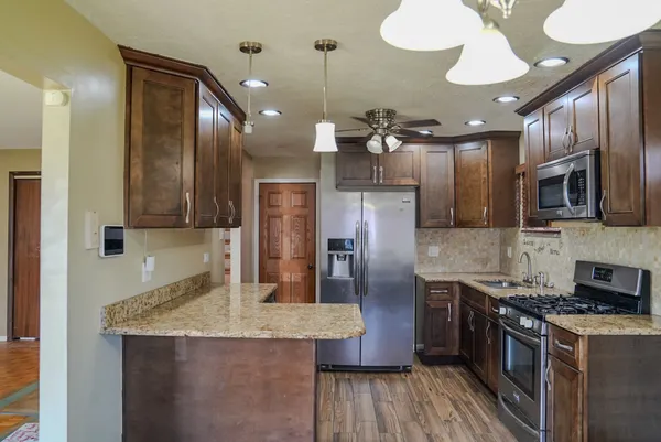 a kitchen with stainless steel appliances granite countertop a sink a stove and a refrigerator