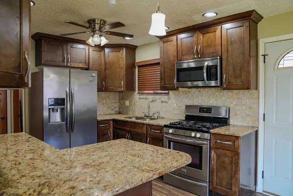 a kitchen with stainless steel appliances granite countertop a stove refrigerator and microwave