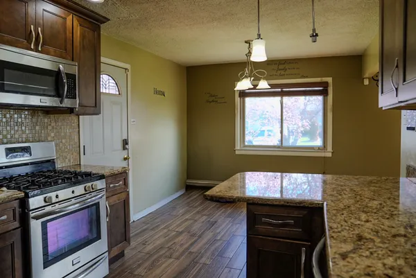 a kitchen with stainless steel appliances granite countertop a stove a sink and a microwave