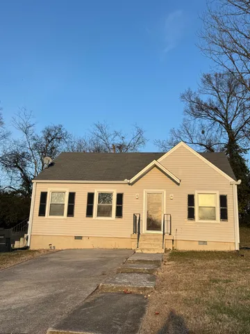 a view of a white house with a big yard and large tree