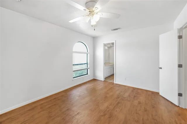an empty room with chandelier fan and windows