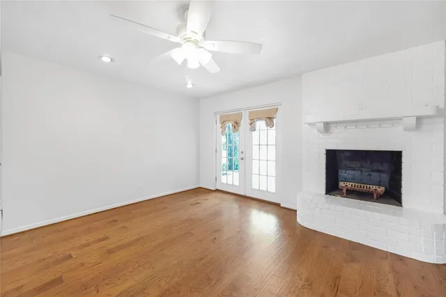 an empty room with wooden floor fireplace cabinet and windows
