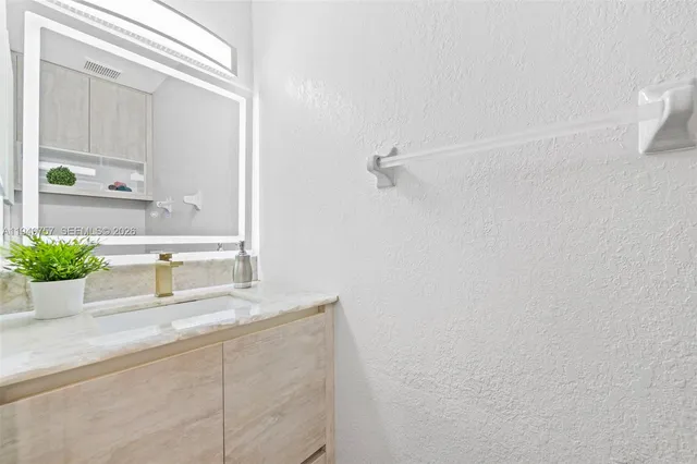 a bathroom with a granite countertop sink and a mirror