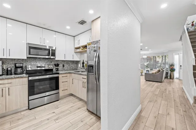 a kitchen with granite countertop a refrigerator stove and a sink