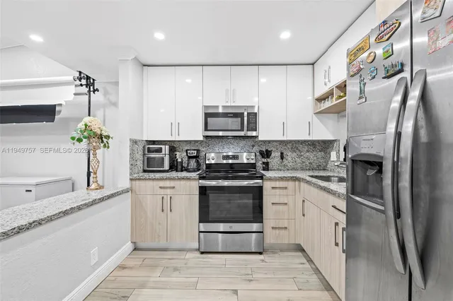 a kitchen with stainless steel appliances granite countertop a stove a sink and a refrigerator