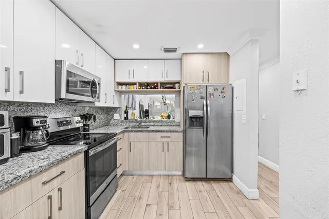 a kitchen with stainless steel appliances granite countertop a refrigerator and a stove top oven