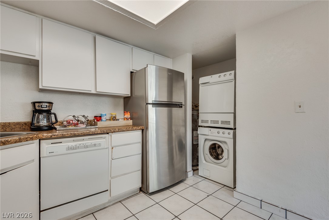 5829 Smoke Ranch Road, Unit D Las Vegas, NV 89108 - Photo 19 of 27 Functional tile flooring matches the clean white cabinetry and integrated laundry setup.