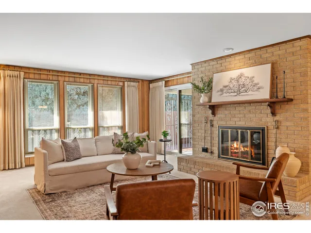 a living room with furniture a fireplace and floor to ceiling windows