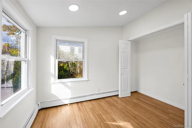 a view of an empty room with window and wooden floor