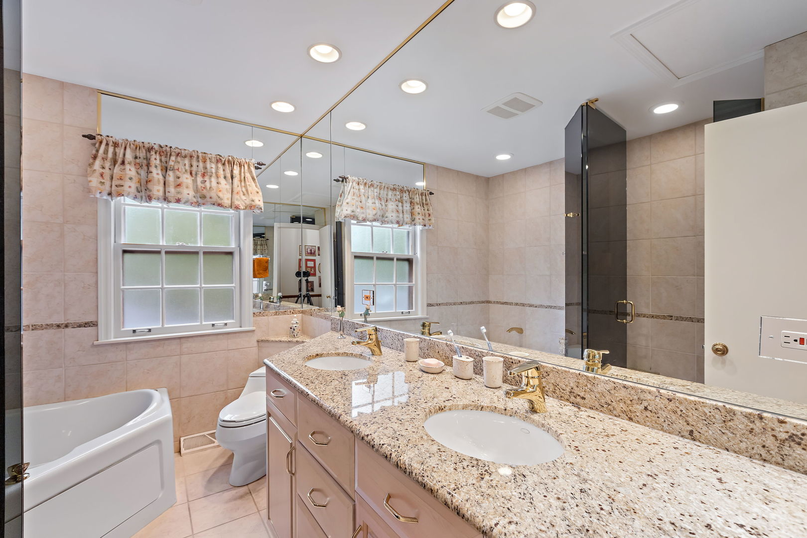 1369 Tower Road Winnetka, IL 60093 - Photo 19 of 31 a bathroom with a granite countertop sink a mirror a bathtub and shower