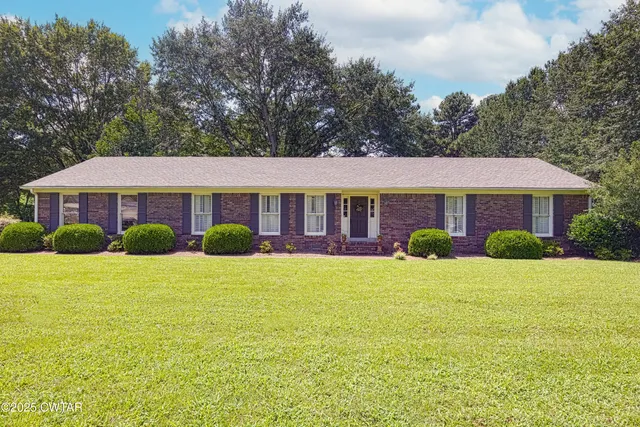 a front view of a house with yard and green space