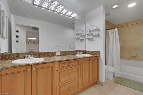 a bathroom with a granite countertop sink a toilet and shower