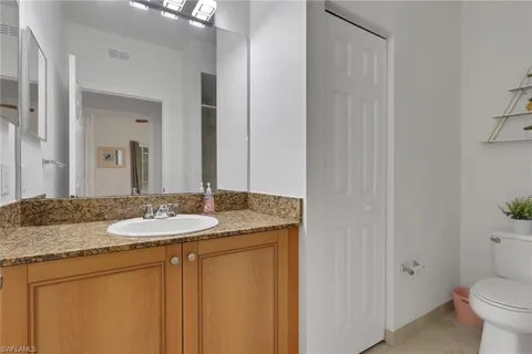 a bathroom with a granite countertop sink and a mirror with toilet