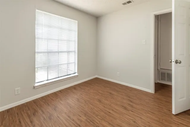 an empty room with wooden floor and windows