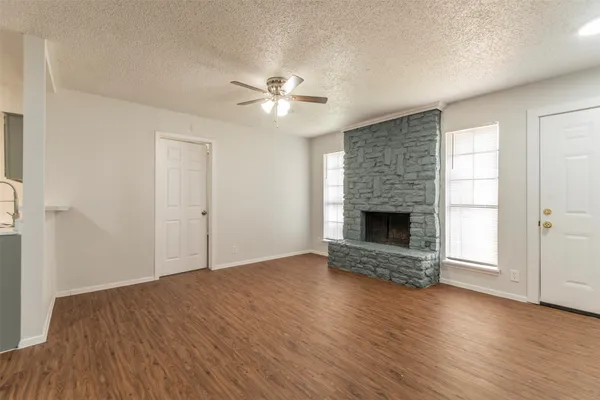 an empty room with wooden floor a fireplace and entryway