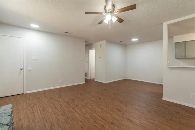 an empty room with wooden floor and ceiling fan