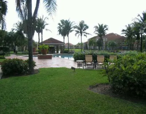 a backyard of a house with table and chairs potted plants and palm trees