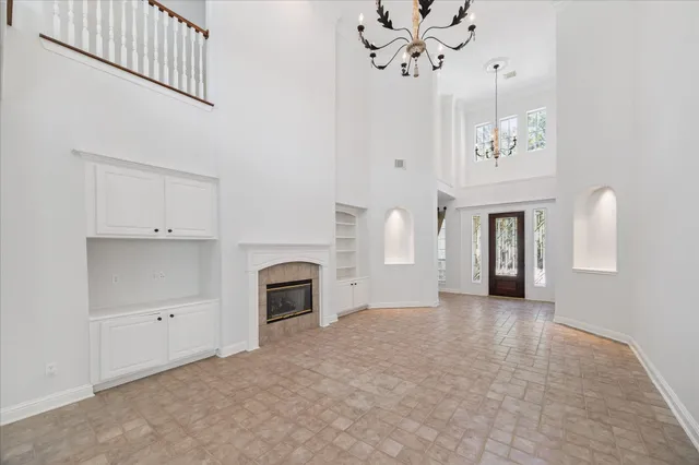 a view of a livingroom with a fireplace a chandelier and windows