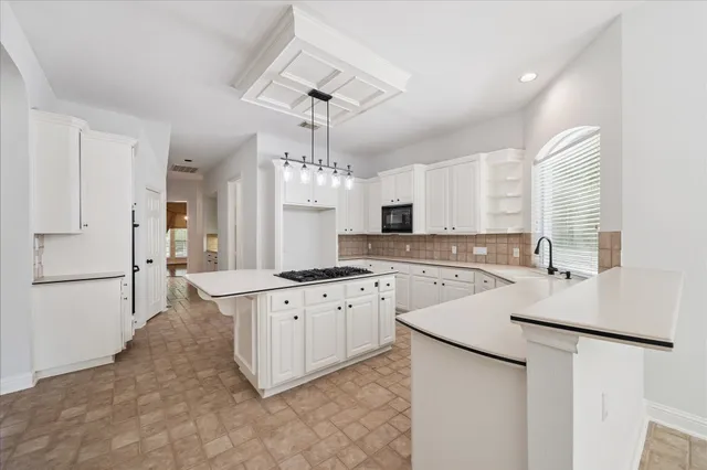 a large kitchen with granite countertop a white refrigerator a sink dishwasher a dining table and chairs with wooden floor