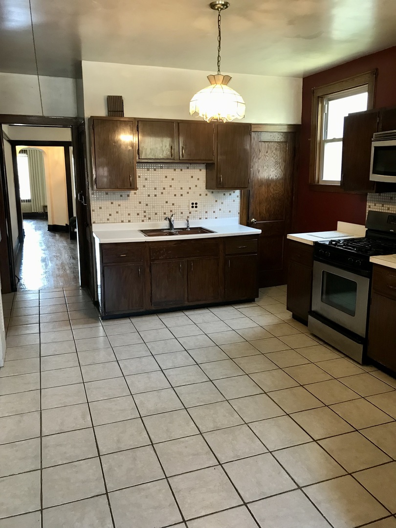 3246 West 65th Street Chicago, IL 60629 - Photo 12 of 50 a kitchen with stainless steel appliances a sink stove and cabinets