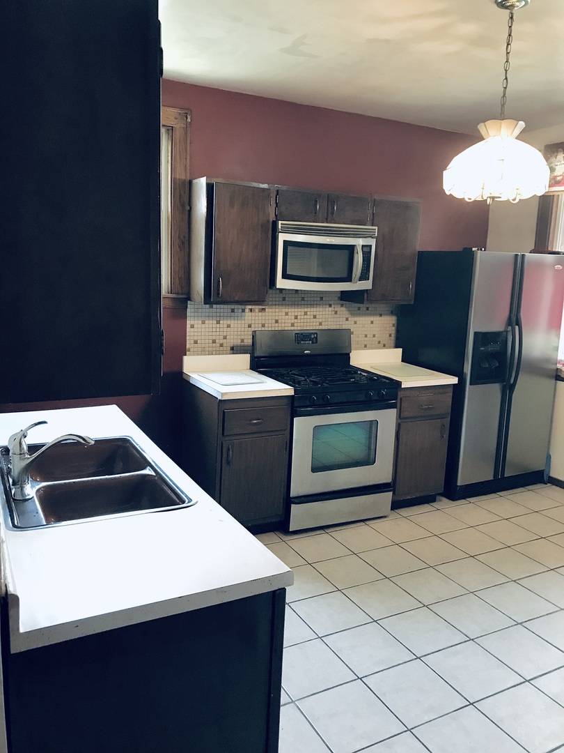 3246 West 65th Street Chicago, IL 60629 - Photo 13 of 50 a kitchen with a sink a microwave a refrigerator and cabinets