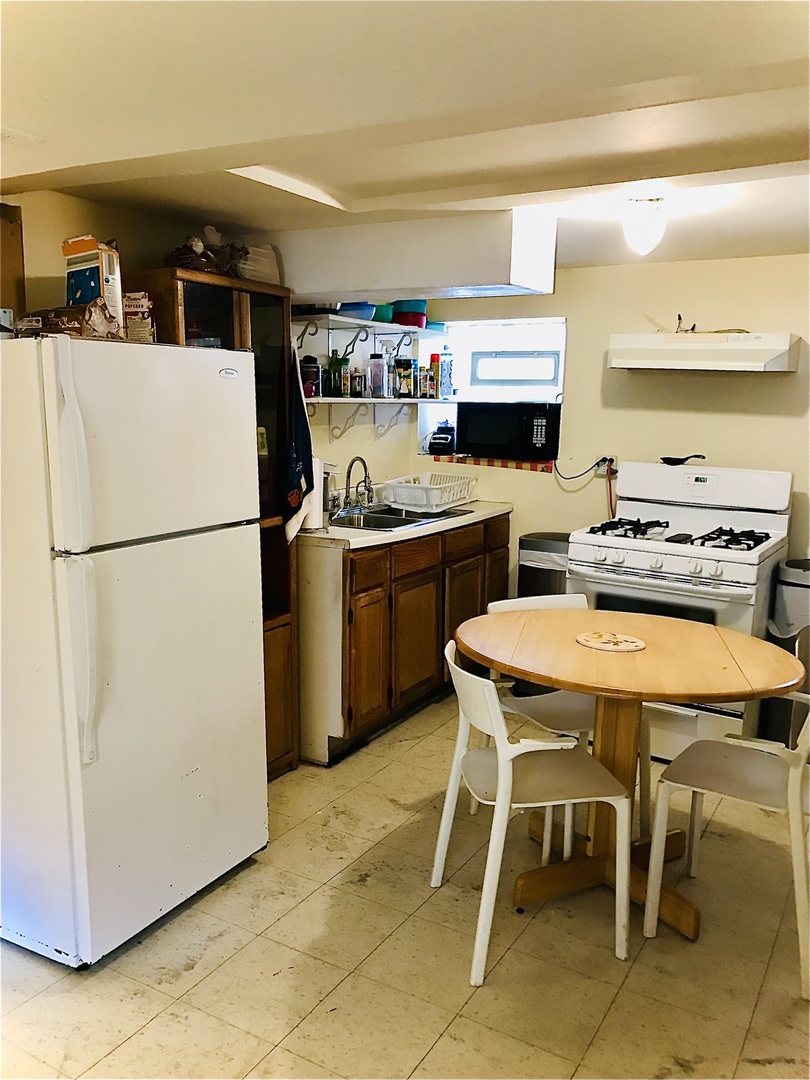 3246 West 65th Street Chicago, IL 60629 - Photo 32 of 50 a white kitchen with a refrigerator a stove a sink and a dining table