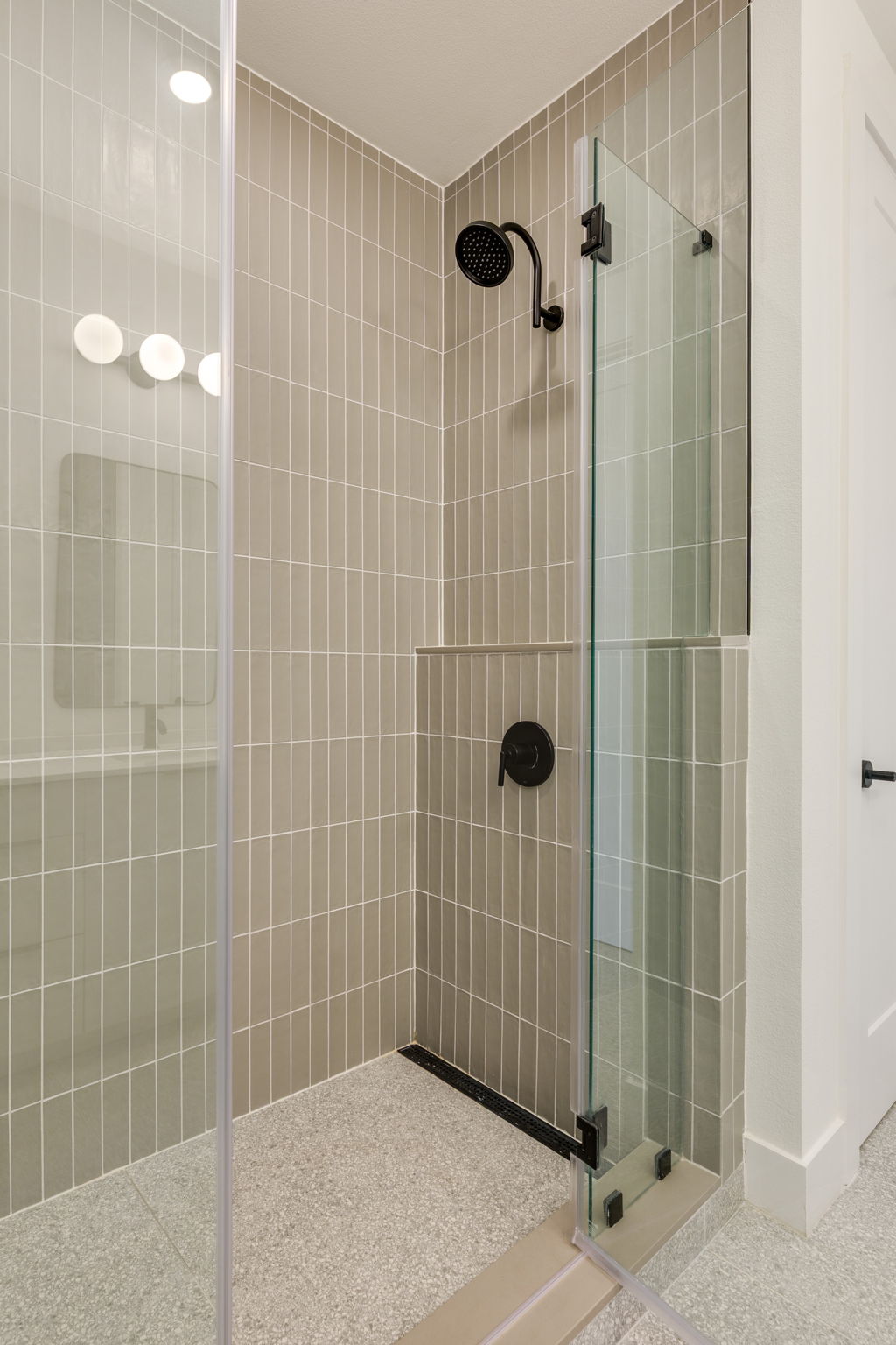 1701 Simond Avenue, Unit 618 Austin, TX 78723 - Photo 11 of 38 The shower features vertical tile walls, a rain showerhead, and a glass enclosure with matte black hardware