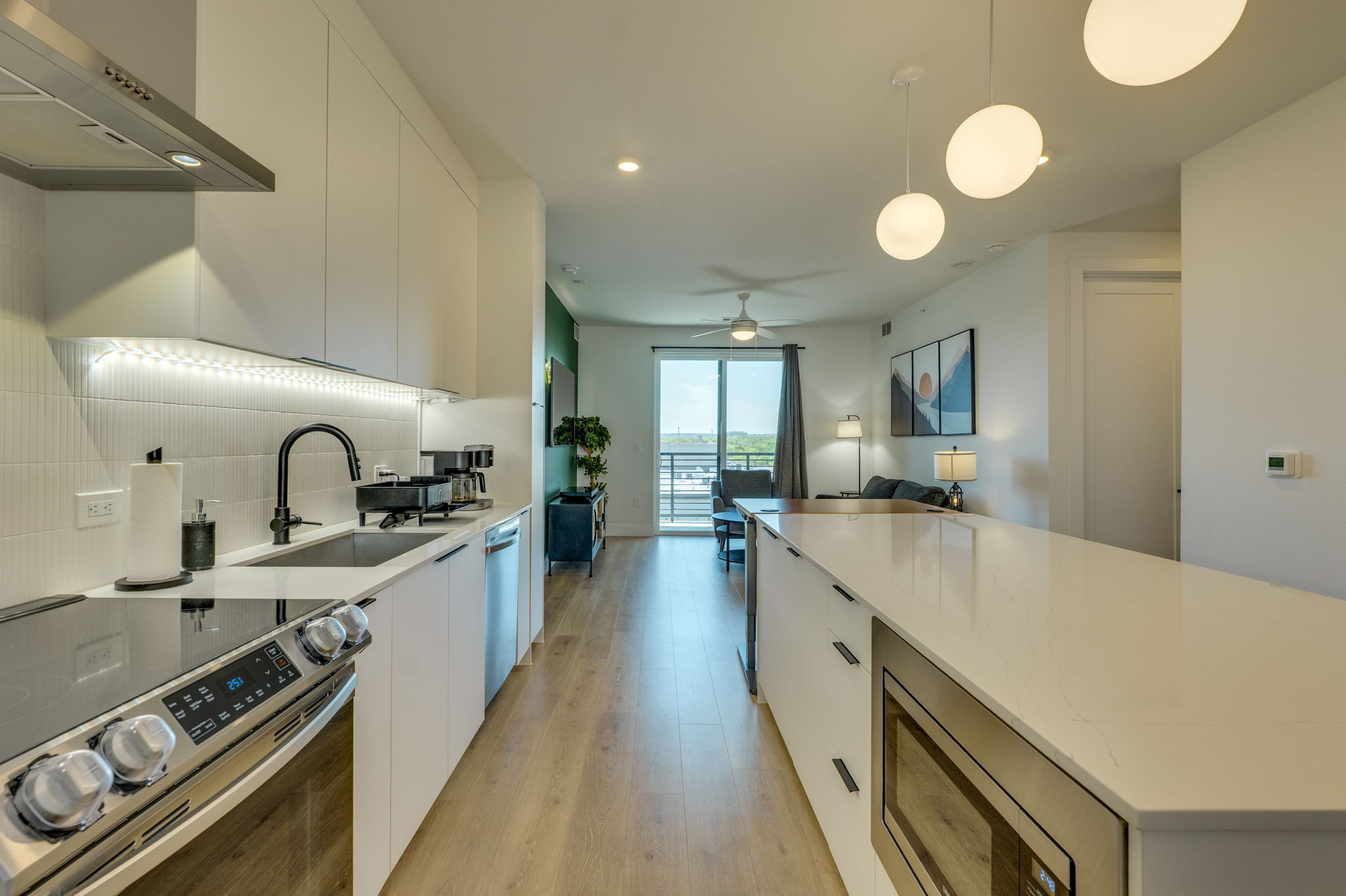 1701 Simond Avenue, Unit 618 Austin, TX 78723 - Photo 2 of 38 The kitchen features white cabinetry, a stainless steel range with a ventilation hood, a black sink faucet, and under-cabinet lighting
