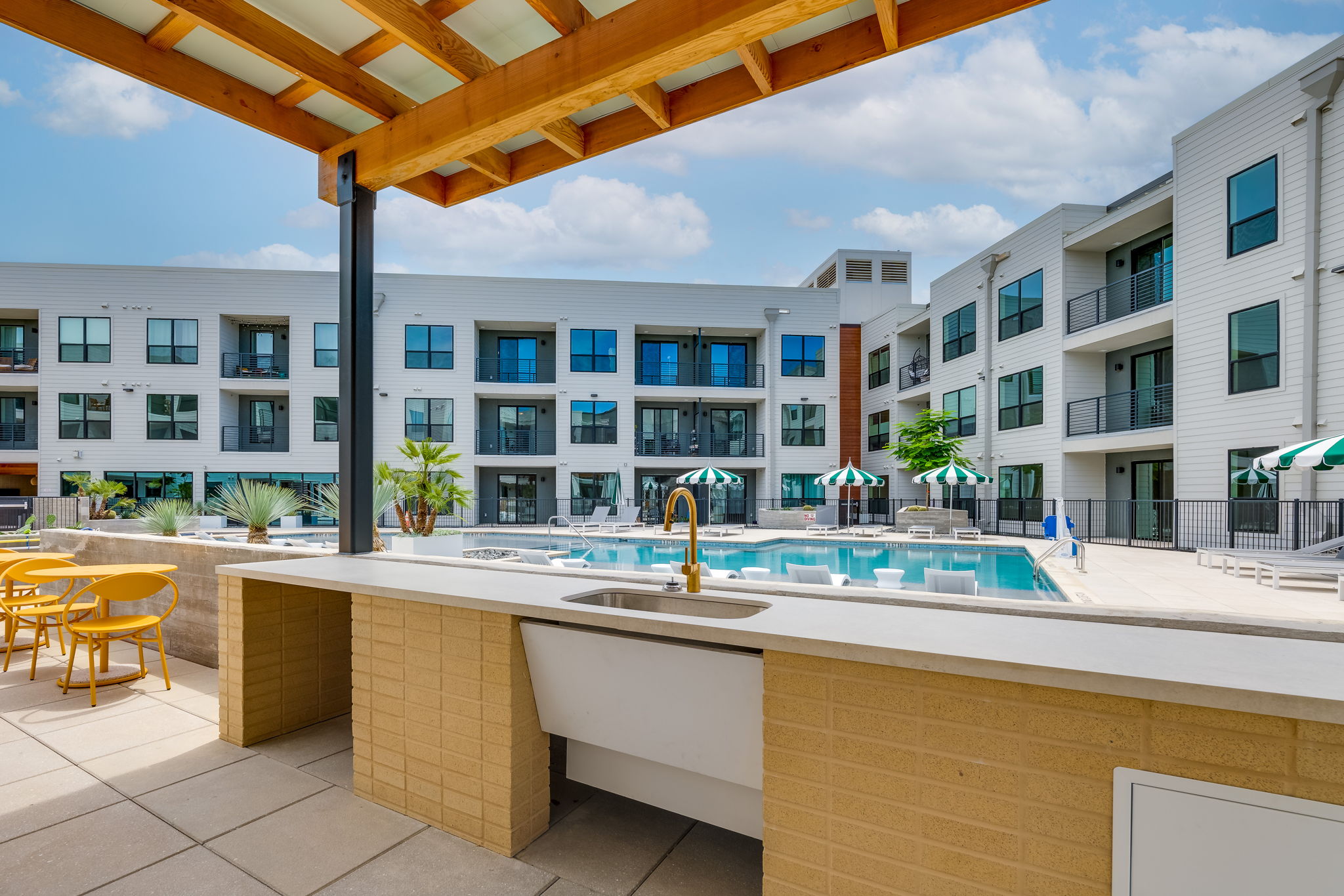 1701 Simond Avenue, Unit 618 Austin, TX 78723 - Photo 22 of 38 Outdoor kitchen with a countertop, sink, and golden faucet, overlooking the swimming pool and surrounding buildings
