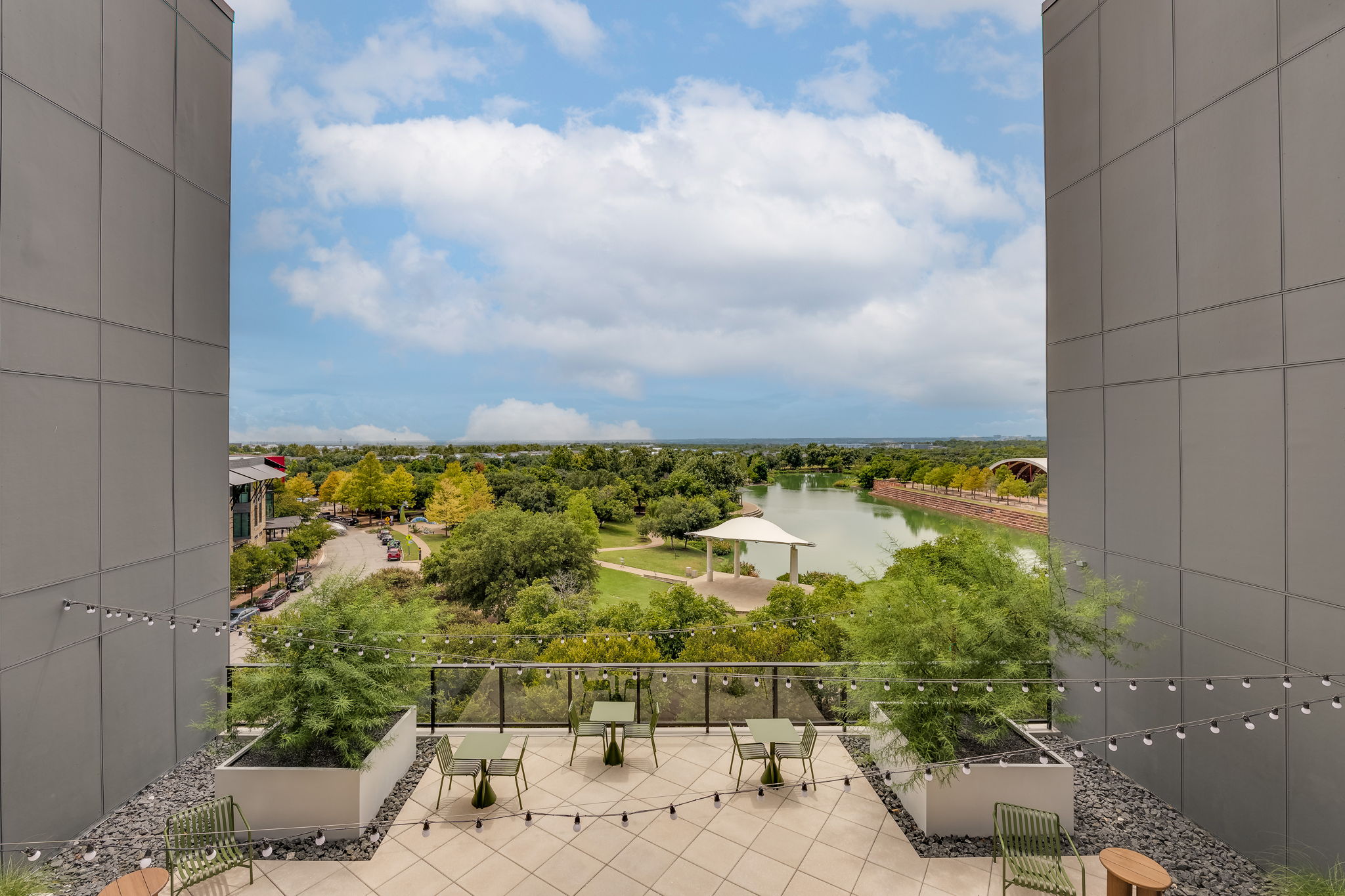 1701 Simond Avenue, Unit 618 Austin, TX 78723 - Photo 24 of 38 Spacious outdoor patio area with tiled flooring and string lights, offering expansive views of a lake and green landscape