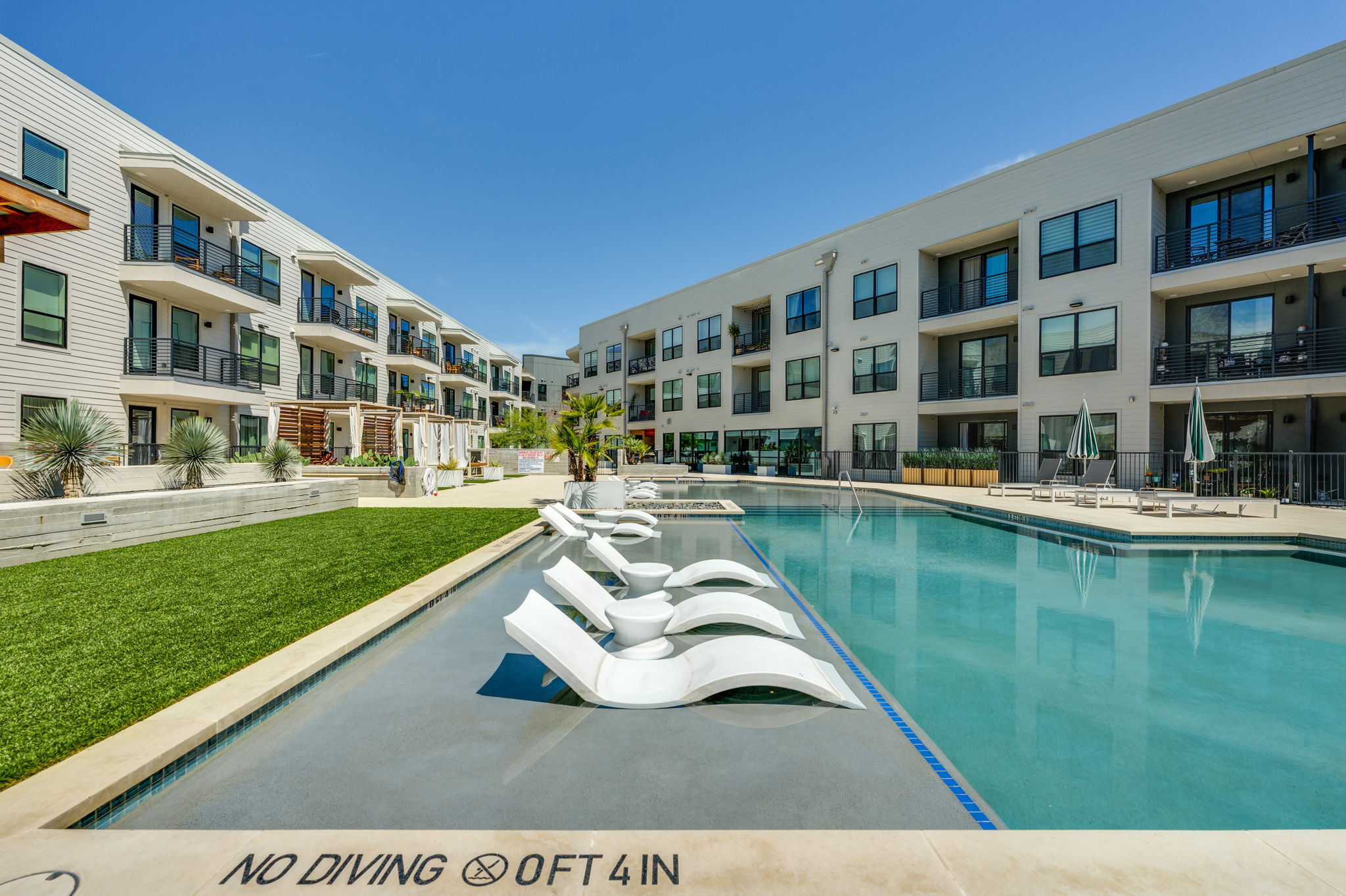 1701 Simond Avenue, Unit 618 Austin, TX 78723 - Photo 27 of 38 The property features a large swimming pool with in-pool loungers, surrounded by landscaped turf areas and paved walkways