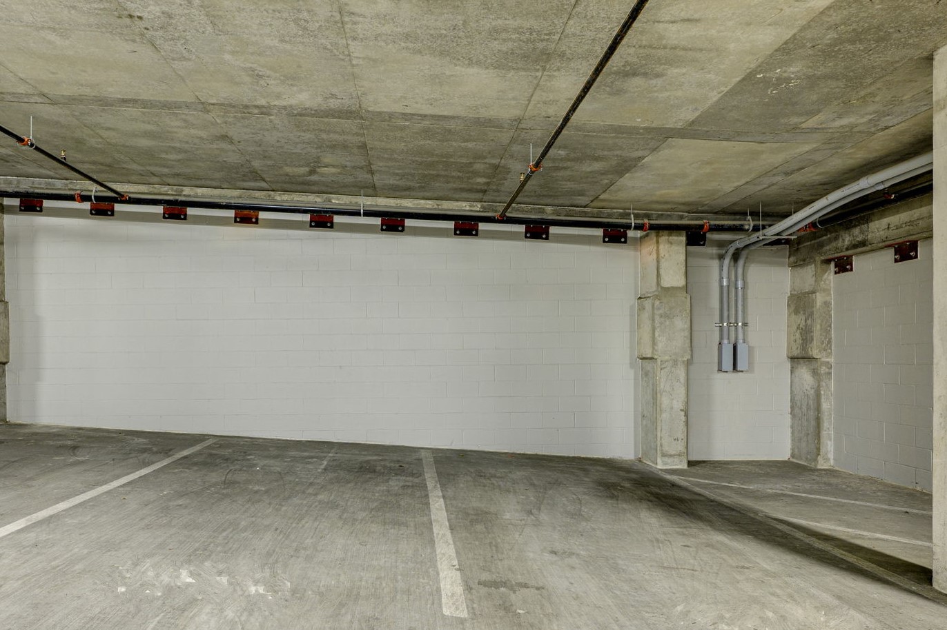 1701 Simond Avenue, Unit 618 Austin, TX 78723 - Photo 29 of 38 Dedicated parking space within a concrete parking structure, featuring painted block walls and exposed concrete ceiling