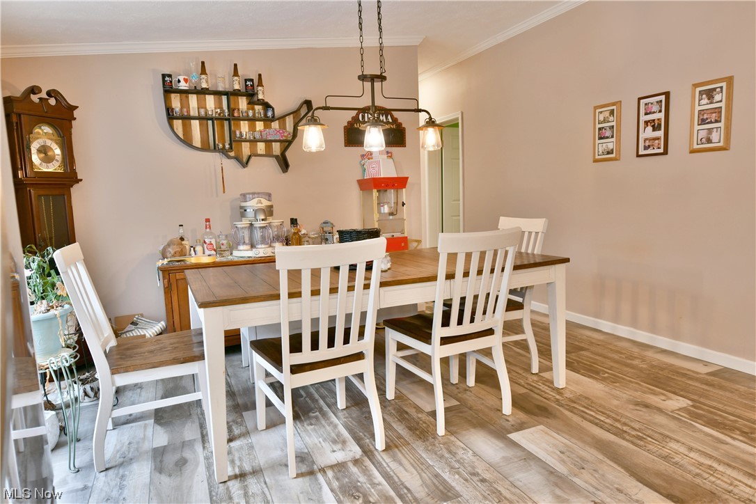 1570 Kale Adams Road Southwest Warren, OH 44481 - Photo 16 of 34 Dining room featuring light wood-type flooring, crown molding, and a notable chandelier